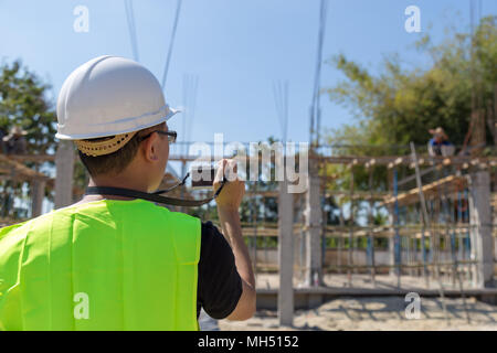 Engineers wear a helmet and holding construction plan and camera monitoring the construction area. Stock Photo