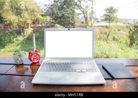 Computer laptop and mouse pen on wood table outdoor and nature background. The blank screen with copy space for your text or advertising content. Stock Photo