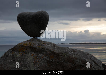heart shaped rock balanced on a boulder Stock Photo