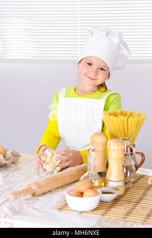 Cute little girl in chef's hat baking cake in the kitchen  Stock Photo