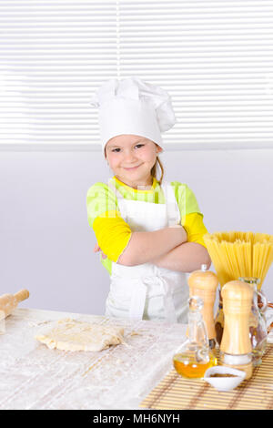 Cute little girl in chef's hat baking cake in the kitchen  Stock Photo