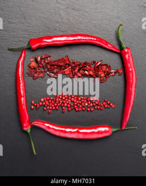 Red hot chili peppeprs and peppercorns on black stone background. top view Stock Photo