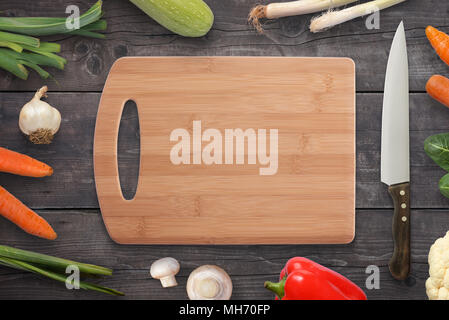 Cutting board vegetables and knife on wooden desk in kitchen. Top view. Free space for logo promotion or text. Stock Photo