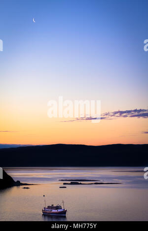 Boat on the water during dusk just before sunrise with the moon and blue and orange color Stock Photo