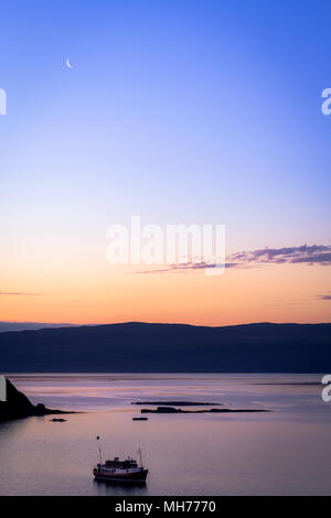 Boat on the water during dusk just before sunrise with the moon and blue and orange color Stock Photo