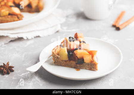 Piece of vegan apple pie with cinnamon, raisins and caramel, gray background. Stock Photo