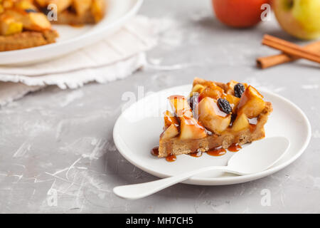 Piece of vegan apple pie with cinnamon, raisins and caramel, gray background. Stock Photo