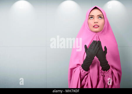 Pretty asian female muslim pray to god in indoor Stock Photo
