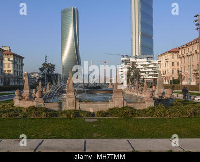 public garden between palaces and skyscrapers with a beautiful fountain with water jets in Milan, Italy Stock Photo