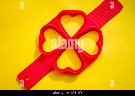 https://l450v.alamy.com/450v/mh81hd/red-silicone-mold-on-a-yellow-backgroundsilicone-heart-shape-egg-ring-for-frying-panfrying-egg-with-silicone-form-and-teflon-pan-molds-for-baking-puncakesbakery-products-mh81hd.jpg