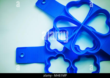 Silicone heart, flowers shape molds on blue background.Tool for baking cookies, puncakes, eggs.Silicone molds for baking cupcakes.Confectionery mold for baking Stock Photo
