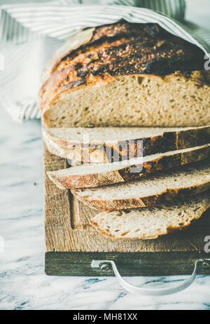 Freshly baked sourdough bread cut into pieces on rustic board Stock Photo