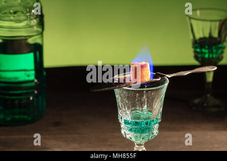 Bottle of absinthe and glasses with burning cube brown sugar. Stock Photo