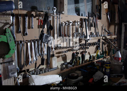 Tools hanging neatly organised on the wall of a garage workshop Stock Photo