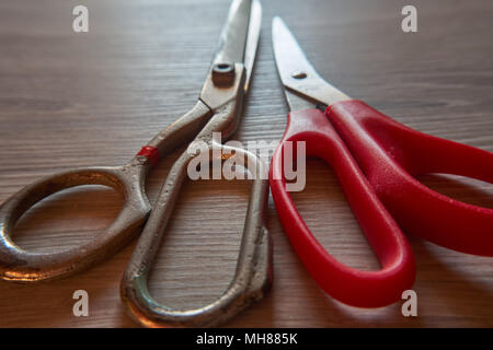 Old pair of scissors on grey wooden background. Retro sewing accessories for home sewing and repair of clothing. Stock Photo