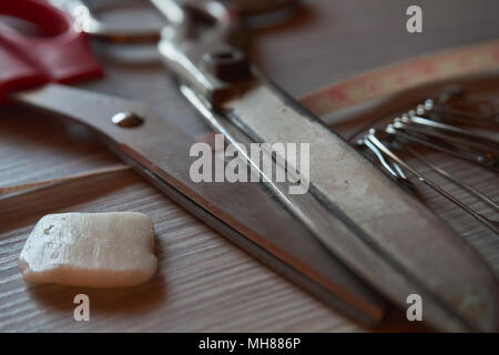 Old metal scissors, chalk, safety pins and tailor measure tape on grey wooden background. Retro sewing accessories for home sewing and repair of cloth Stock Photo