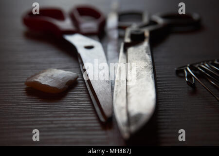 Old metal scissors, chalk and safety pins on grey wooden background. Retro sewing accessories for home sewing and repair of clothing. Stock Photo