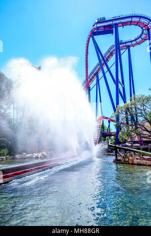 A High modern rollercoaster with a splash pool in the foreground