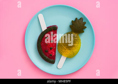 Pineapple and watermelon popsicles on pink background. Top view Stock Photo