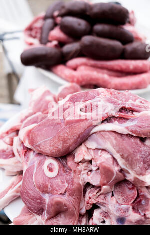 closeup of a pile of slices of raw pork and lamb meat and some raw sausages in the background Stock Photo
