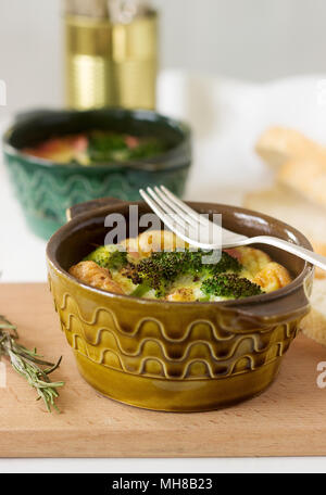 Baked scrambled eggs with broccoli, sausages and cheese served with slices of bread. Rustic style, selective focus. Stock Photo