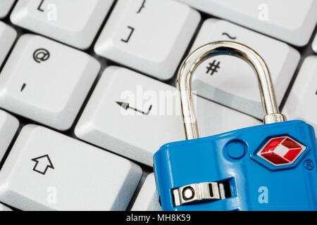 A keyboard with enter key and a TSA padlock to illustrate online cyber security and data protection concept. Focused on padlock. England, UK, Britain Stock Photo