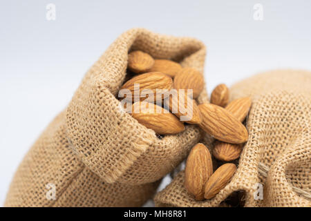 Almonds group in woven sack on white background. Select focus shallow depth of field Stock Photo