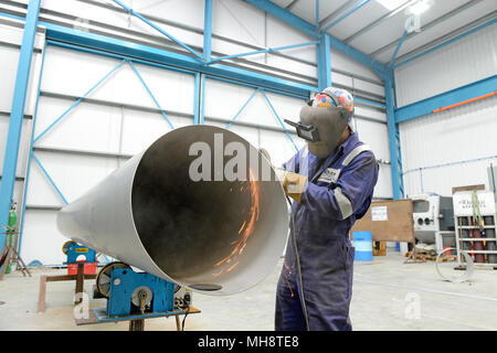 Man cutting large pipe with grinder in engineering workshop Stock Photo
