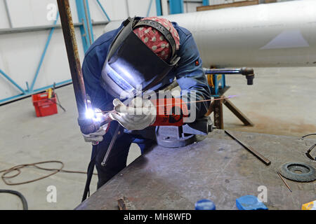 Welder welding pipe together in a fabrication workshop Stock Photo