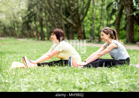 Young and elder woman doing yoga in the park Stock Photo