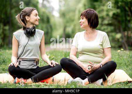 Young and elder woman doing yoga in the park Stock Photo