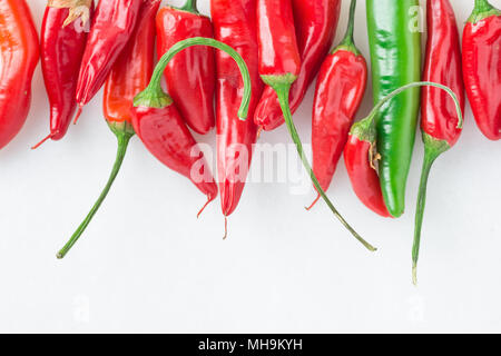 Row of Colorful Red and Green Hot Spicy Chili Peppers on White Marble Stone Background. Upper Border. Food Poster. Mexican Cuisine Stock Photo