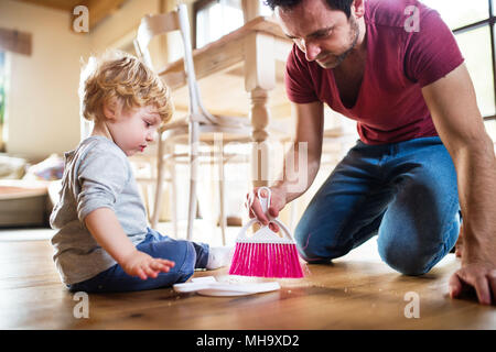 Handsome father and toddler boy with brush and dustpan. Stock Photo