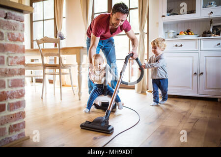 Father and two toddlers doing housework. Stock Photo