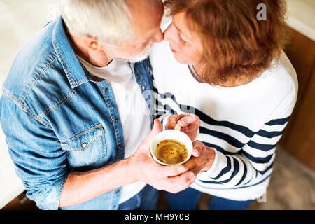 Unrecognizable senior couple holding a cup of coffee at home. Stock Photo