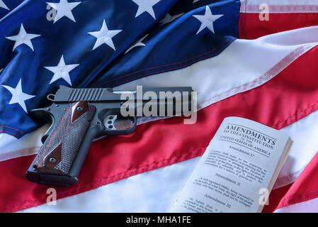 The second amendment and gun control in the US, concept. A handgun and the american constitution on the USA flag. Stock Photo