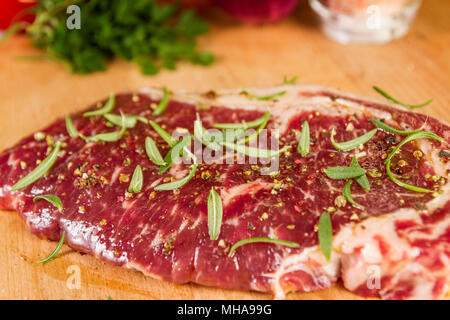 Ripened seasoned beef rump or striploin steak  on wooden cut board prepared for cooking Stock Photo