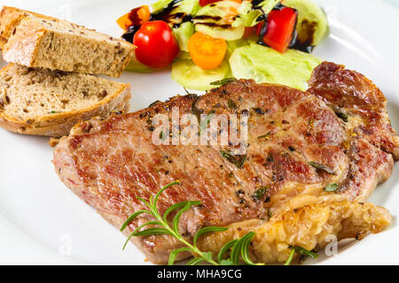 Ripened seasoned beef rump or striploin steak cooked on white plate with salad and home made bread Stock Photo