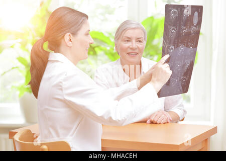 Female middle aged doctor of radiology showing her delighted senior patient the latest mri of her head Stock Photo