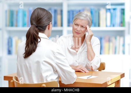 Female doctor with her senior patient with sleeping trouble, suffering of chronic headaches or migraine Stock Photo