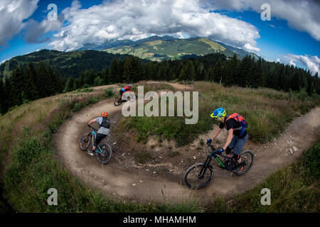Three mountain bikers ride a man made trail in Les Gets bikepark in the Portes du Soleil ski area in the French Alps. Stock Photo