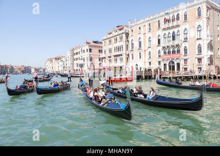Several gondolas with tourists enjoying a sightseeing tour of the city on the Grand Canal at St Marks Basin,  Venice, Veneto, Italy Stock Photo