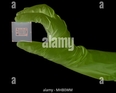 Hand wearing gloves holding a CPU computer processor microchip on black Stock Photo