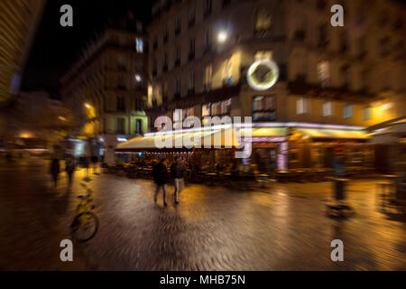 Blurry motion image of people walking on street at night in Paris. Stock Photo