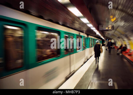 Blurry motion image of woman walking and a train in subway station in Paris. Stock Photo