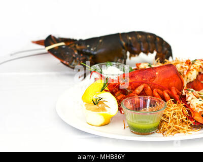 Live and cooked lobster served with the vegetables on a white plate. Isolated Stock Photo