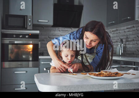 Happy family in the kitchen. Holiday food concept. Mother and daughter decorate cookies. Happy family in making homemade pastry. Homemade food and little helper Stock Photo