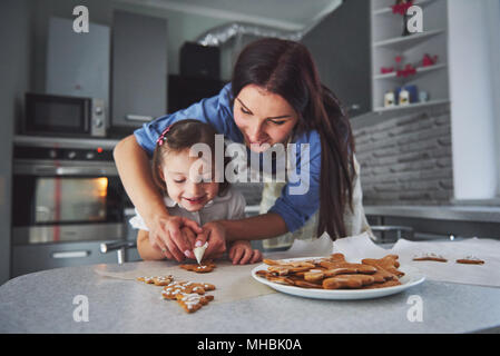 Happy family in the kitchen. Holiday food concept. Mother and daughter decorate cookies. Happy family in making homemade pastry. Homemade food and little helper Stock Photo