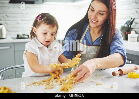 Happy family in the kitchen. Holiday food concept. Mother and daughter preparing the dough, bake cookies. Happy family in making cookies at home. Homemade food and little helper Stock Photo