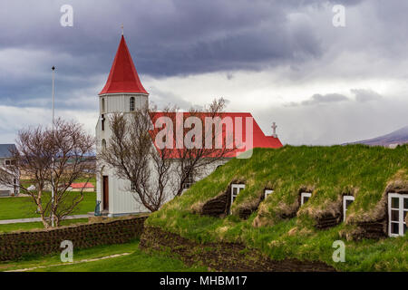 Red roofed church in Glaumbaer village and small cottages with turf roofs in Northern Iceland Stock Photo